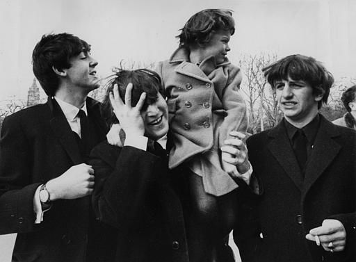 John Lennon, center, holds his forehead as 5-year-old Debbie Fyall, of London, England, sits on his shoulders, in Central Park, February 8, 1964. <span class=meta>AP Photo</span>