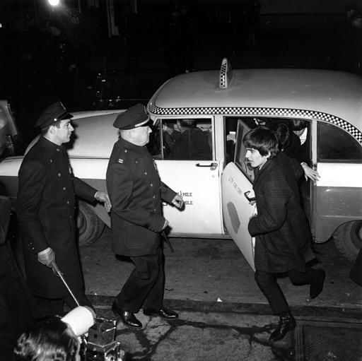 Police security is on hand as guitarist George Harrison leads the way from a taxi-cab to Carnegie Hall's stagedoor on W. 56th St. on Feb. 12, 1964. <span class=meta>AP Photo</span>