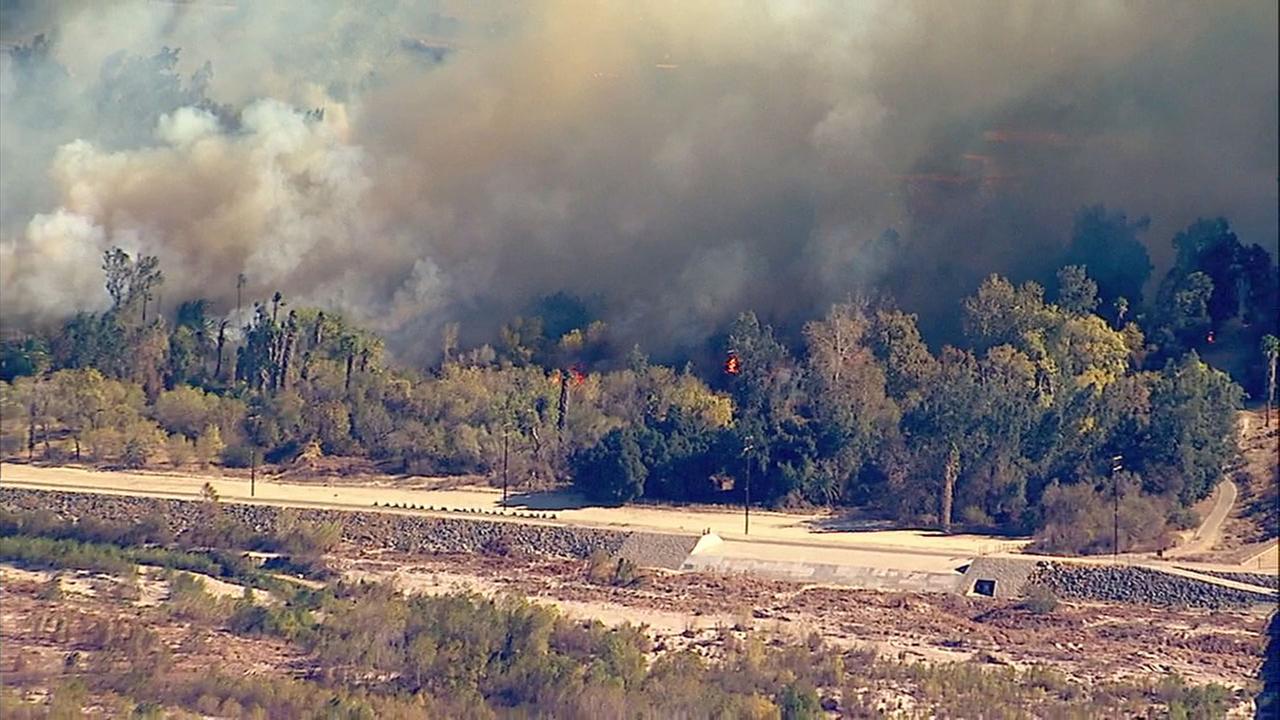 Smoke and flames cover acres of land near the Santa Ana river bottom in Riverside on Thursday, Dec. 21, 2017.