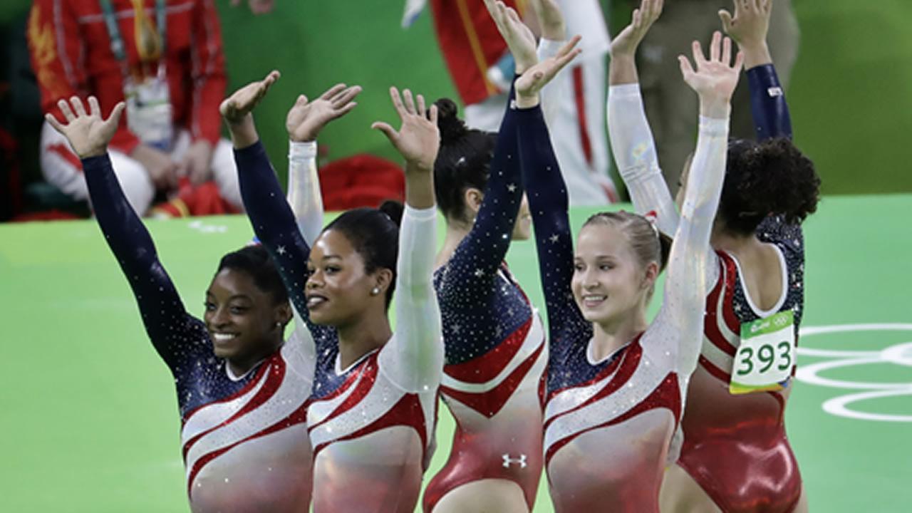 U.S. gymnasts, left to right, Simone Biles, Gabrielle Douglas, Aly Raisman, Madison Kocian, and Lauren Hernandez wave at 2016 Summer Olympics in Rio de Janeiro, Aug. 9, 2016.