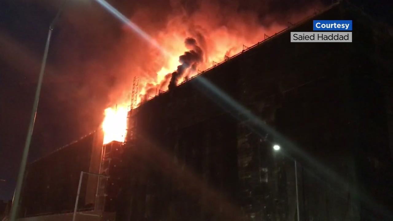 Flames spill out of a building under construction in Oakland Calif. on Friday