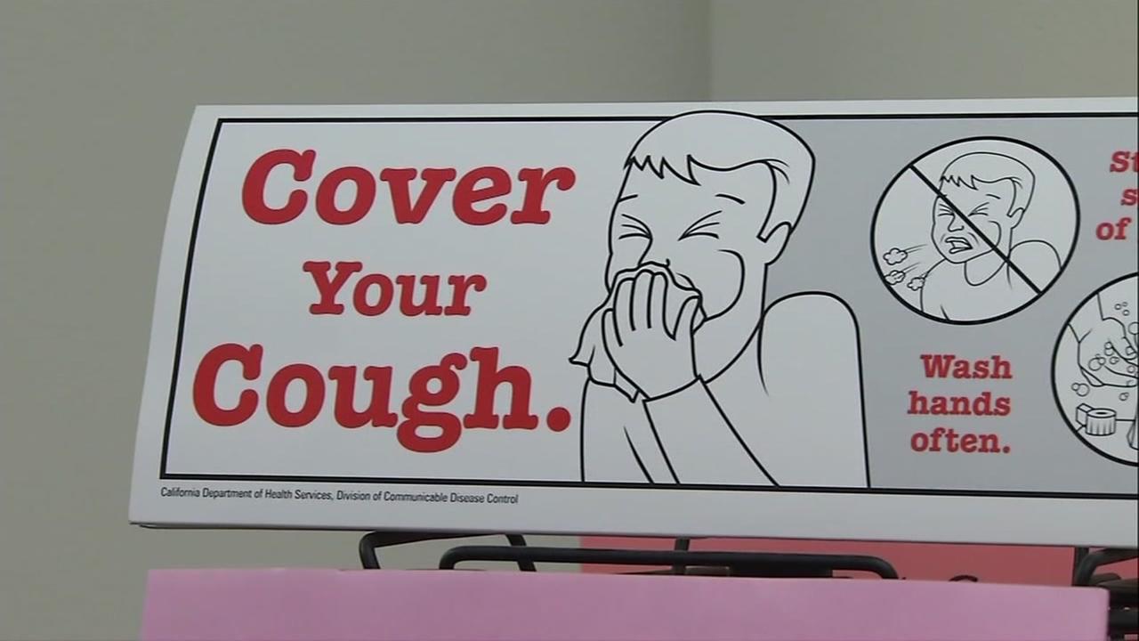 A sign reads, Cover your cough.