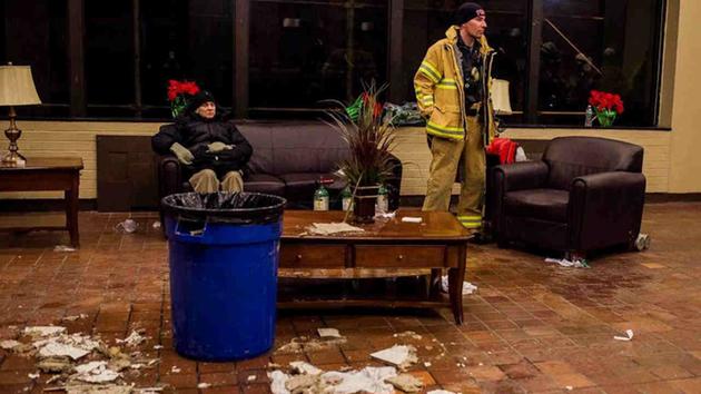 <div class='meta'><div class='origin-logo' data-origin='AP'></div><span class='caption-text' data-credit='Andres Kudacki'>Water leaks from a broken roof as a man rests near a firefighter in the lounge of a high-rise building after a fire is under control on the west side Thursday.</span></div>