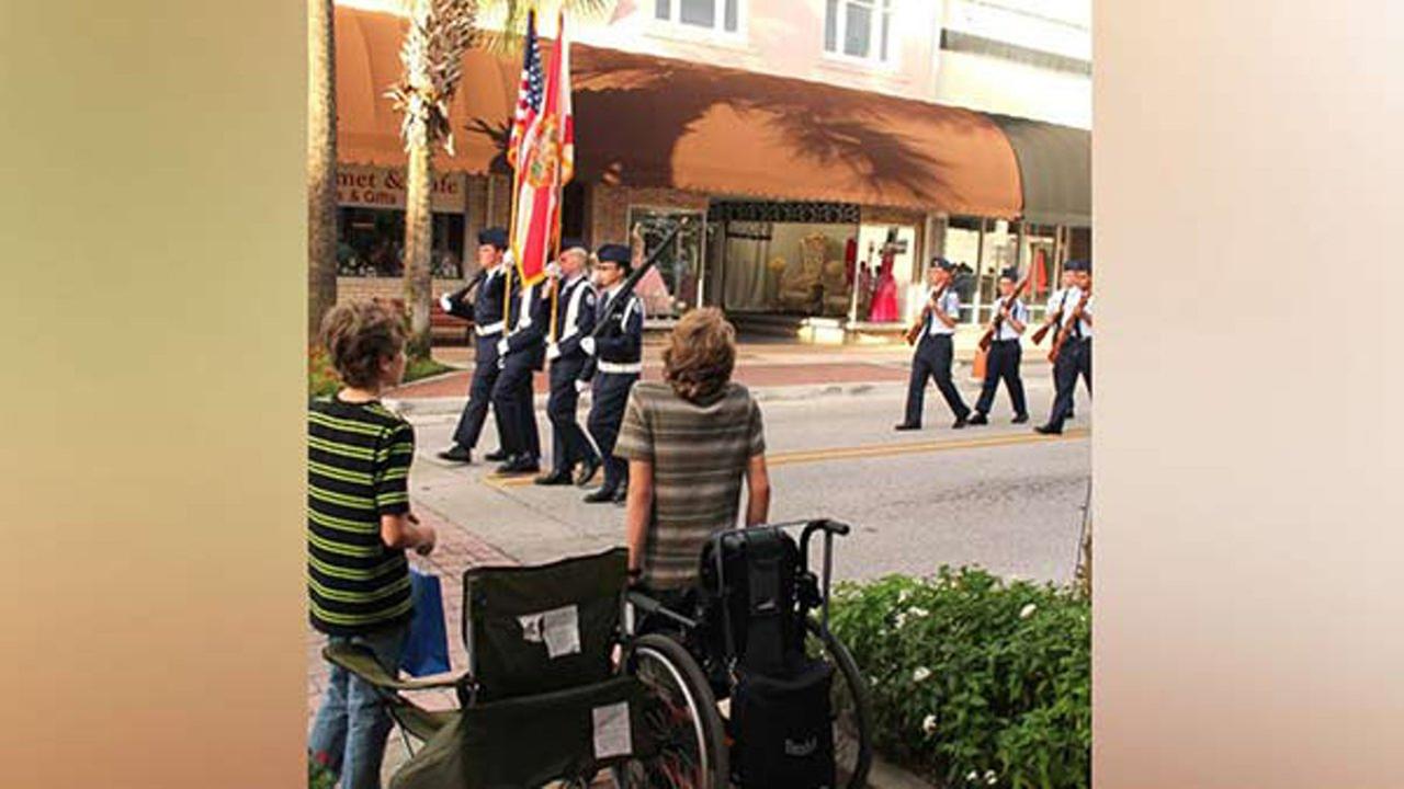 Teen in wheelchair stands for American flag
