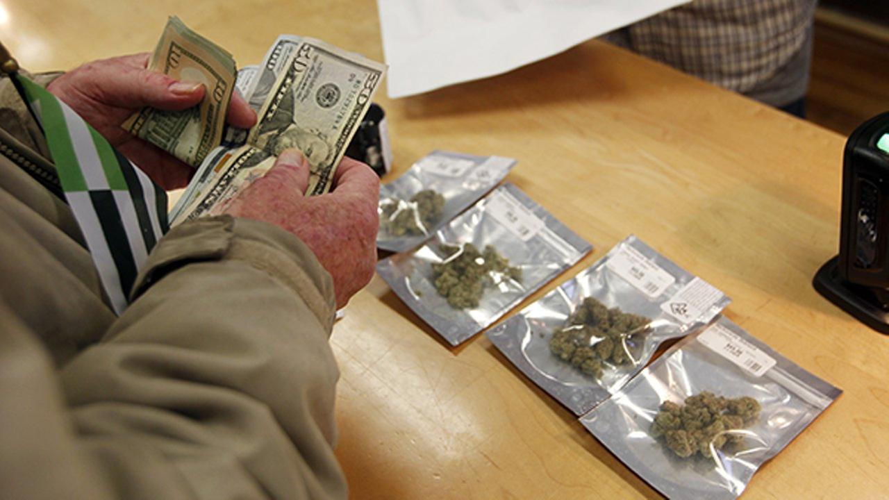 A customer purchases marijuana at Harborside marijuana dispensary, Monday, Jan. 1, 2018, in Oakland, Calif.
