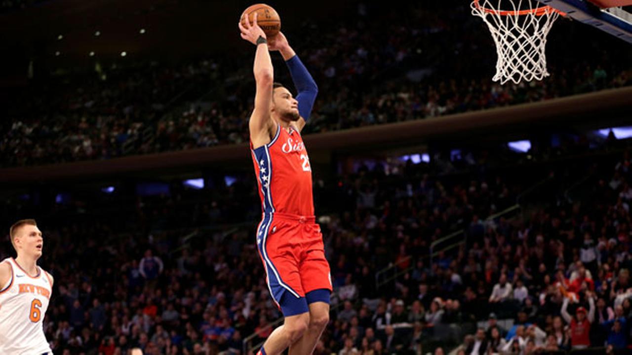 While New York Knicks Kristaps Porzingis, left, watches as Philadelphia 76ers Ben Simmons goes up for a dunk.