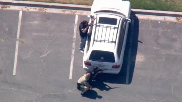 In this photo, police are seen in a Long Beach parking in a tactical position after cornering an armed-robbery suspect that led them on a chase from Redlands to Long Beach, Monday, June 21, 2010.