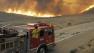 Fire engines pause as flames from a fast moving wildfire approach Elizabeth Lake Road in the Leona Valley near Palmdale, Calif. on Thursday, July 29, 2010.