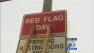A sign indicates that a red flag warning is in effect and parking restrictions will be enforced.