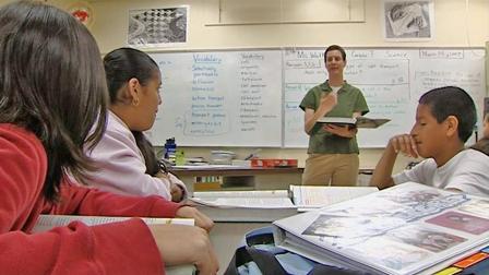 A teacher is seen with students in a classroom.