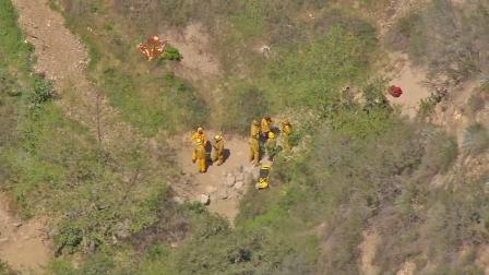 Firefighters are seen in Eaton Canyon where two hikers fell on Friday, March 22, 2013. One of the hikers died and the other was hospitalized.