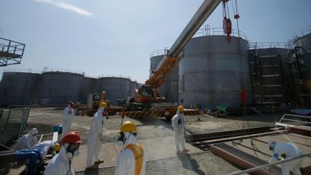 FILE - In this Wednesday, March 6, 2013 file photo, workers wearing protective gears take a survey near tanks of radiation contaminated water at Tokyo Electric Power Co.s Fukushima Dai-ichi nuclear power plant.