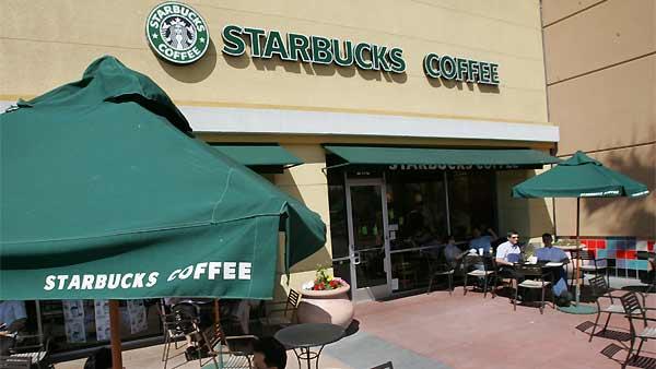Starbucks drinkers sits outside of Starbucks Coffee