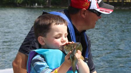 In this photo made Wednesday, June 26, 2013 in Nevis , Minn., Bobby Tufts, the 4-year-old mayor of Dorset, Minn., kisses a fish that his guide, Jason Durham, caught on Lake Belle Taine.