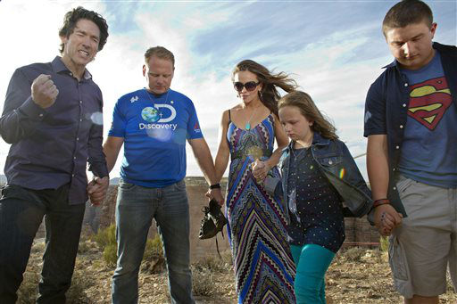 Preacher Joel Osteen, left, leads a prayer with Nik Wallenda, second from left, his wife Erendira, daughter Evita and son Yanni before Wallenda walked a 2-inch-thick steel cable that took him a quarter mile over the Little Colorado River Gorge.
