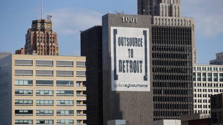 In this July 12, 2013, photo an Outsource to Detroit banner from Galaxe Solutions is seen on a Detroit building.
