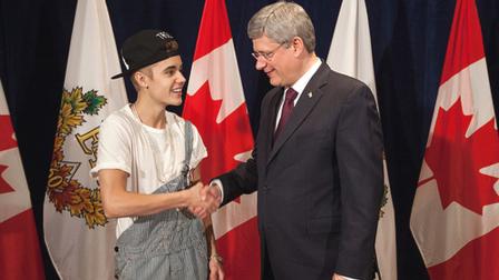 Justin Bieber and Canadian Prime Minister Stephen Harper shake hands after Bieber was awarded the Queen Elizabeth II Diamond Jubilee Medal.
