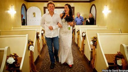 Singer Jon Bon Jovi, left, walks fan Branka Delic, right, down the aisle to give her away at her wedding in Las Vegas on Saturday, Oct. 12, 2013.