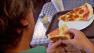 A man is seen eating pizza.
