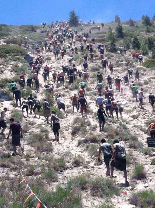 Tough Mudder participants hike up steep terrain,...