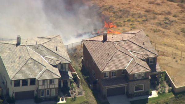 Firefighters battle a fast moving brush fire that broke out near Corona Thursday afternoon along a dry creek bed.