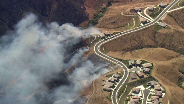 Firefighters battle a fast moving brush fire that broke out near Corona Thursday afternoon along a dry creek bed.