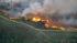 A brush fire is seen in a riverbed in Jurupa...