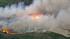 A brush fire is seen in a riverbed in Jurupa...