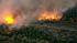 A brush fire is seen in a riverbed in Jurupa...