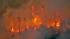 A brush fire is seen in a riverbed in Jurupa...