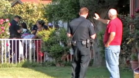 A Corona resident speaks with an officer following a shooting in the neighborhood that left one woman dead and one man injured on Saturday, April 27, 2013.