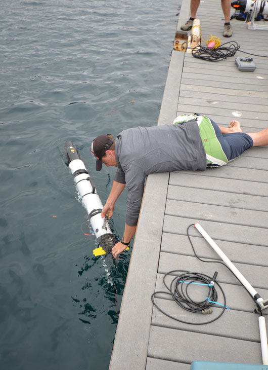 Dr. Chris Clark sets a robot into the water. The...