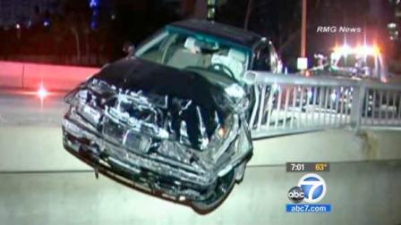 A wrecked BMW hangs over the guardrail of the Fourth Street Bridge atop the 110 Freeway in downtown Los Angeles on Sunday, June 3, 2012.