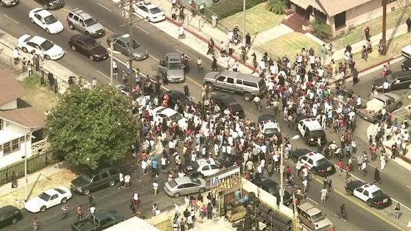 A large crowd of people surrounded police vehicles containing bank robbery suspects in the back at the end of a wild pursuit in South Los Angeles on Wednesday, Sept. 12, 2012.