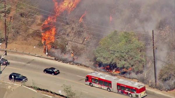Cars are seen driving past a brush fire that erupted in the Sepulveda Pass near the 405 Freeway at Getty Center Drive on Friday, September 14, 2012.