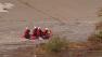 A firefighter team aboard an inflatable boat works to rescue a man stranded in the Los Angeles River on Monday, Dec. 24, 2012.