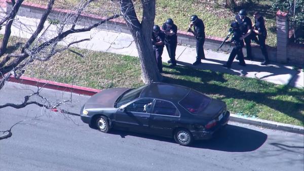 Police officers cautiously approach a vehicle at the end of a pursuit in Panorama City on Friday, Feb. 1, 2013. The suspect sat in his car and inhaled nitrous oxide from balloons.