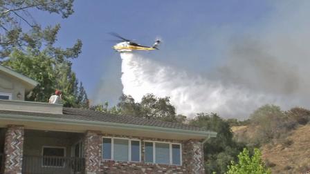 A helicopter drops water on a brush fire in Monrovia on Saturday, April 20, 2013.