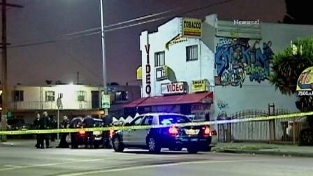 Law enforcement officials are shown behind crime tape at a scene of a deadly drive-by shooting in the 7500 block of South Main Street in South Los Angeles on Thursday, May 23, 2013.k