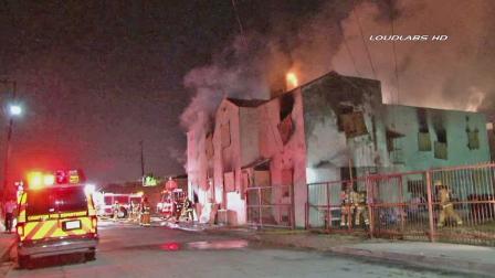Firefighters work to put out a fire in a burning building in Compton Monday, June 10, 2013.