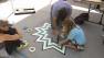 Artists use tape to make a design on the floor at a Big Draw L.A. event in downtown Los Angeles on Sunday, Oct. 13, 2013.