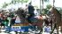 An officer on horseback flanks a crowd of...