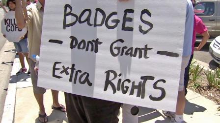 Protesters hold up a sign in response to two fatal officer-involved shootings by Anaheim police.