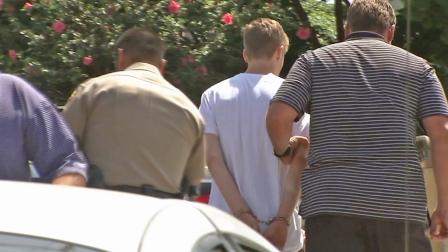 John Kudla, 17, is shown in handcuffs following his arrest Wednesday, May 22, 2013. He is accused of beating his father, 50-year-old Jon Kudla, with a hammer.