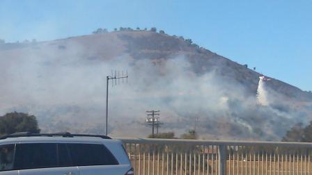 A helicopter flies over a vegetation fire that erupted near Laguna Niguel on Saturday, Sept. 28, 2013.