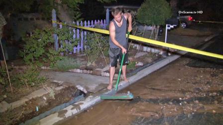 A resident cleans up after a water main break flooded the street on Tuesday, Oct. 15, 2013.