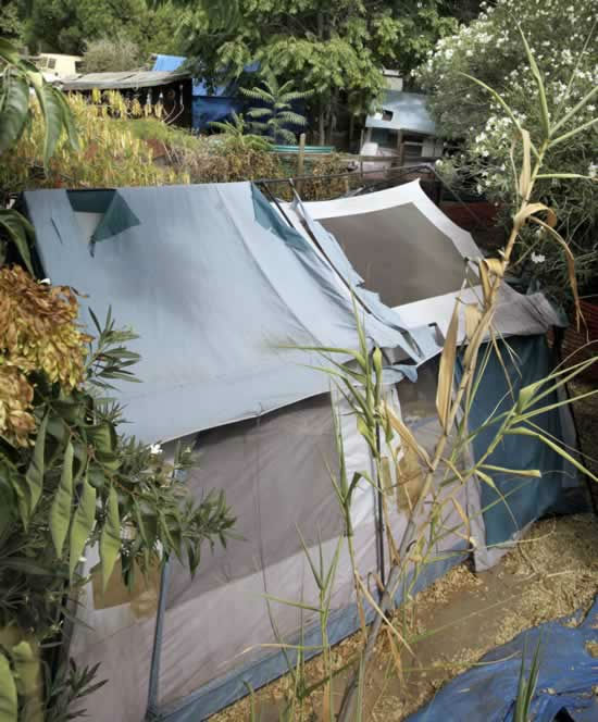 A tent and shacks are shown in the backyards of...