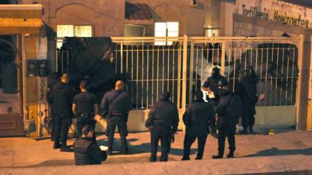 Mexican federal police officers stand outside a home after the exterior gate was covered with a plastic tarp in the northern city of Ciudad Juarez, Mexico, late Friday Oct. 22, 2010.