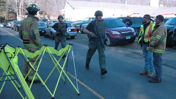 In this photo provided by the Newtown Bee, police officers are on the scene outside Sandy Hook Elementary School in Newtown, Conn., where authorities say a gunman opened fire, killing 26 people, including 20 children, Friday, Dec. 14, 2012.