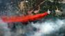 An aircraft lays down a line of fire retardant between a wildfire and homes in the dry, densely wooded Black Forest area northeast of Colorado Springs, Colo., Thursday, June 13, 2013.